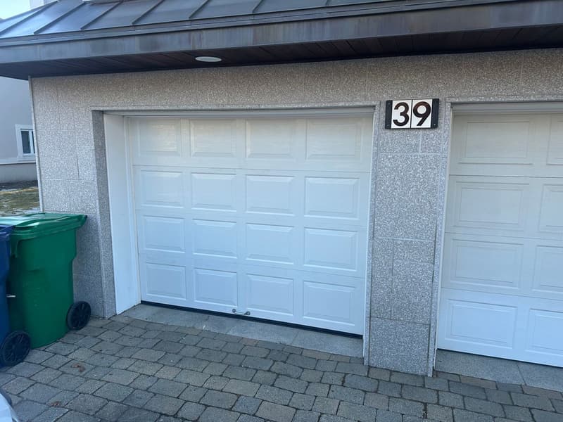 New white raised-panel garage door installed on stone-faced home exterior